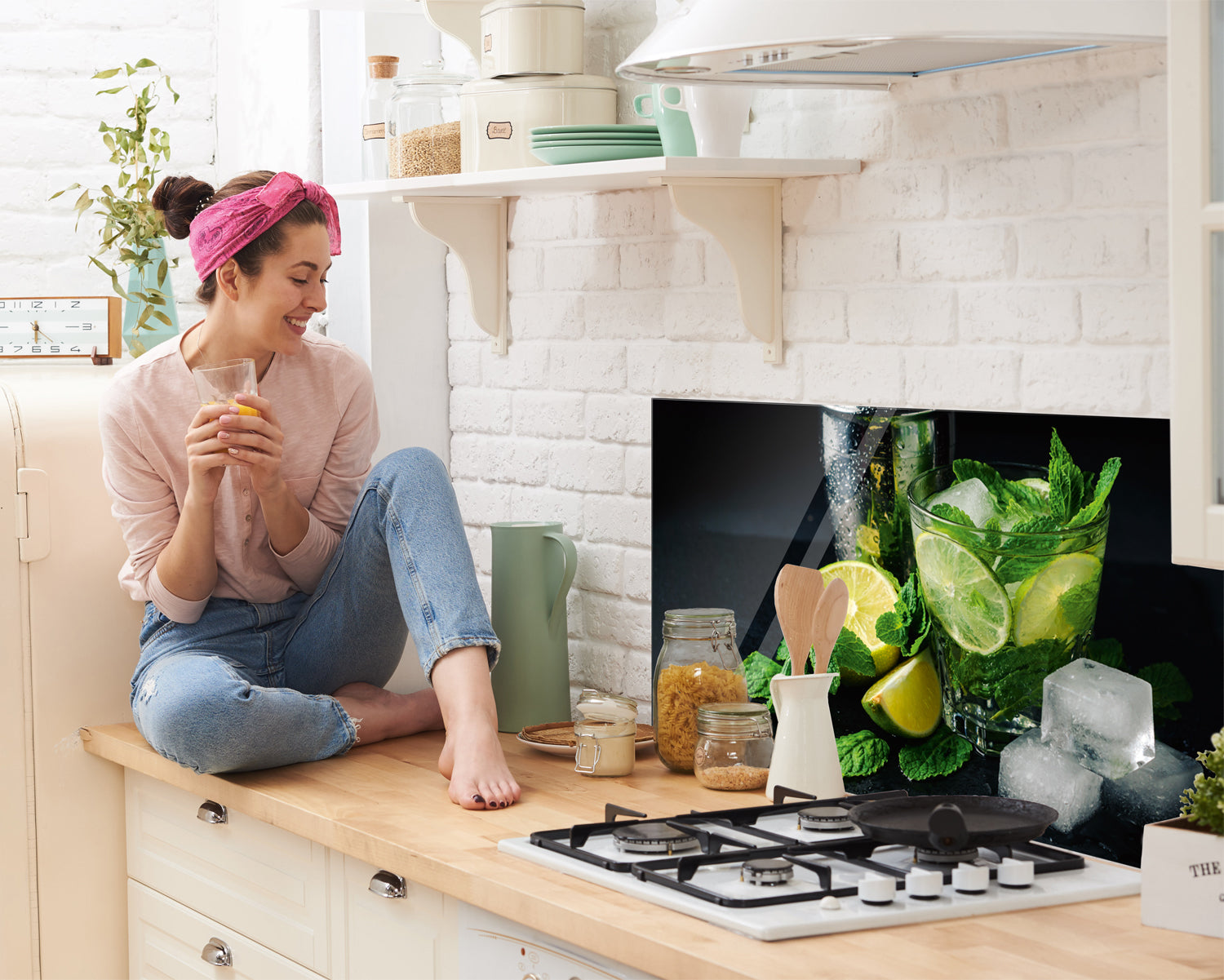 Frau mit Getränk, frische Limetten und Minze, moderne Küche.