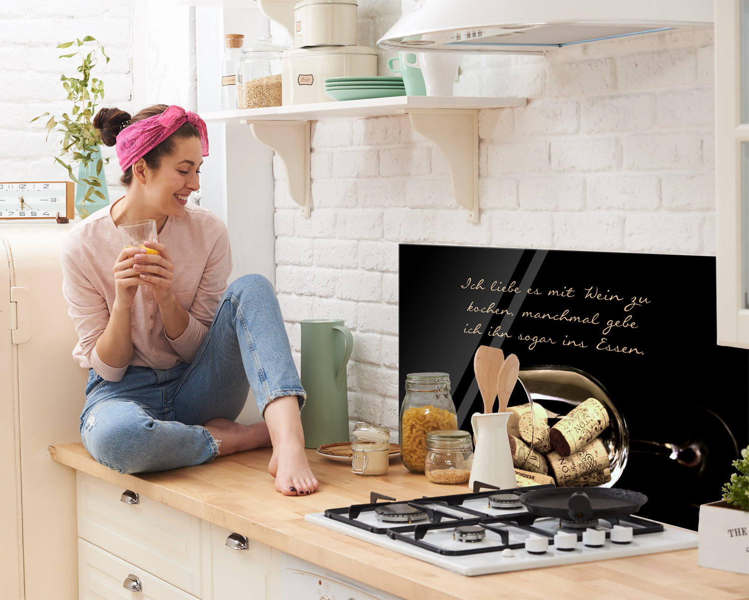 Küchenzeile mit schwarzem Spritzschutz und Kochutensilien.