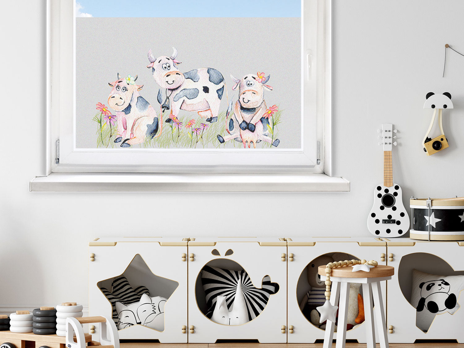 Bunte Kühe mit Blumenmotiv an einem Fenster.