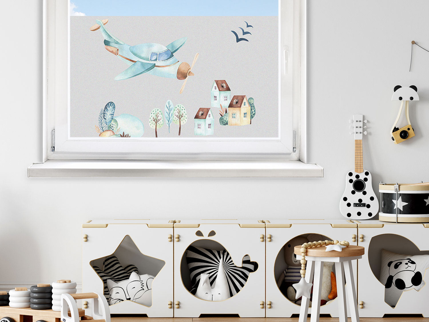 Flugzeug in sanften Farben über Häusern und Bäumen.