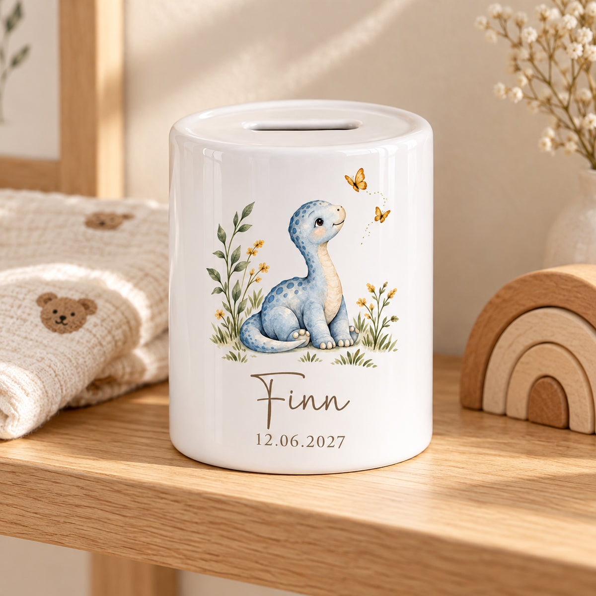 Blauer Dino mit Schmetterlingen: Spardose mit Beispielname Finn und Datum 12.06.2027, Wohnszene