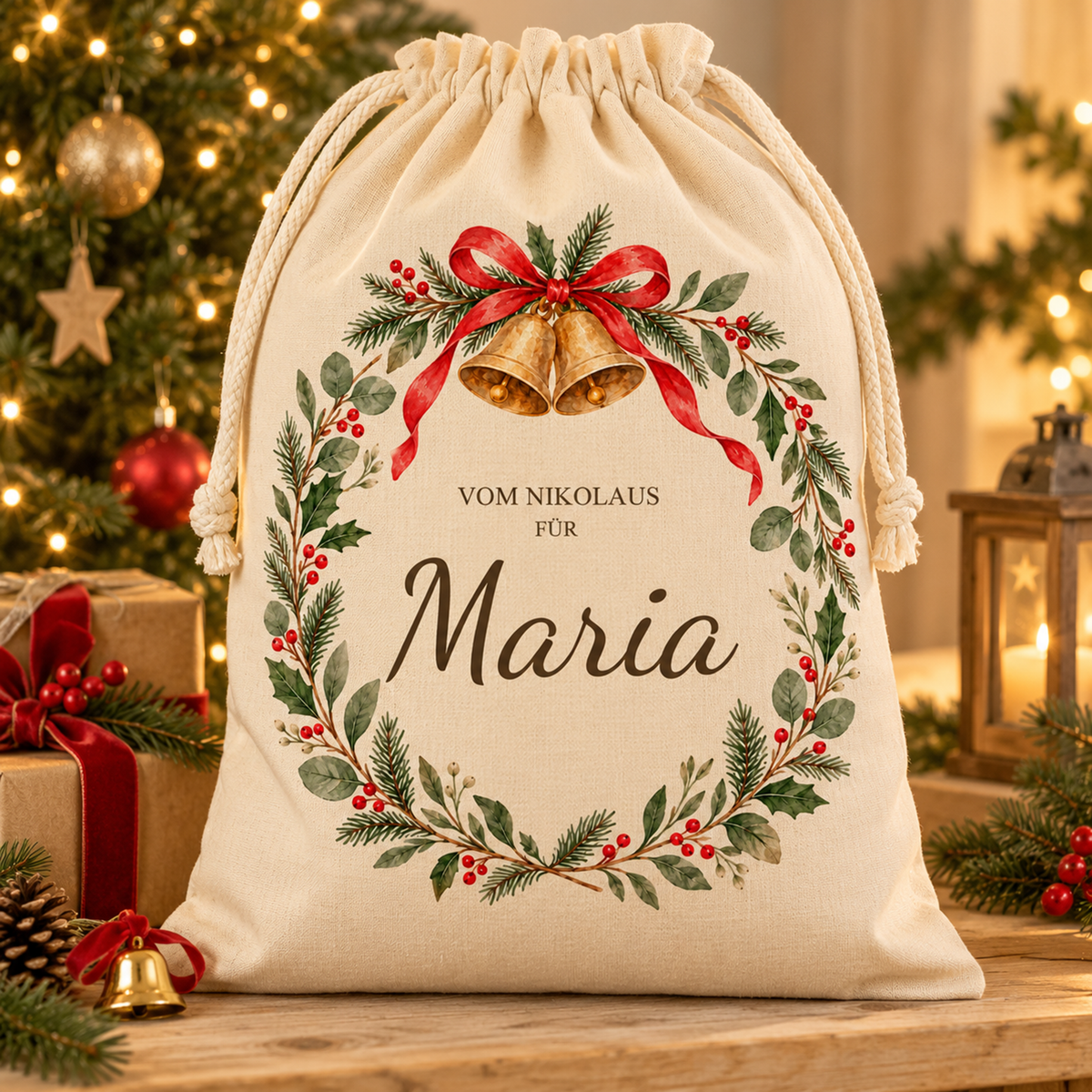 Nikolaussack mit Glöckchenkranz und Wunschname neben verpackten Geschenken vor einem beleuchteten Weihnachtsbaum.