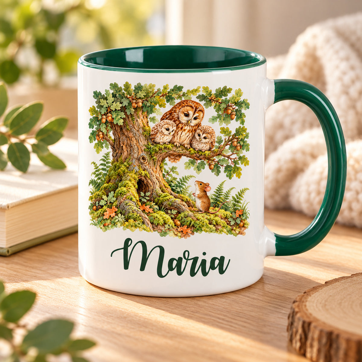 Weiße Namenstasse mit grünem Henkel und Waldmotiv: Eulenfamilie und Maus, auf einem Holztisch.