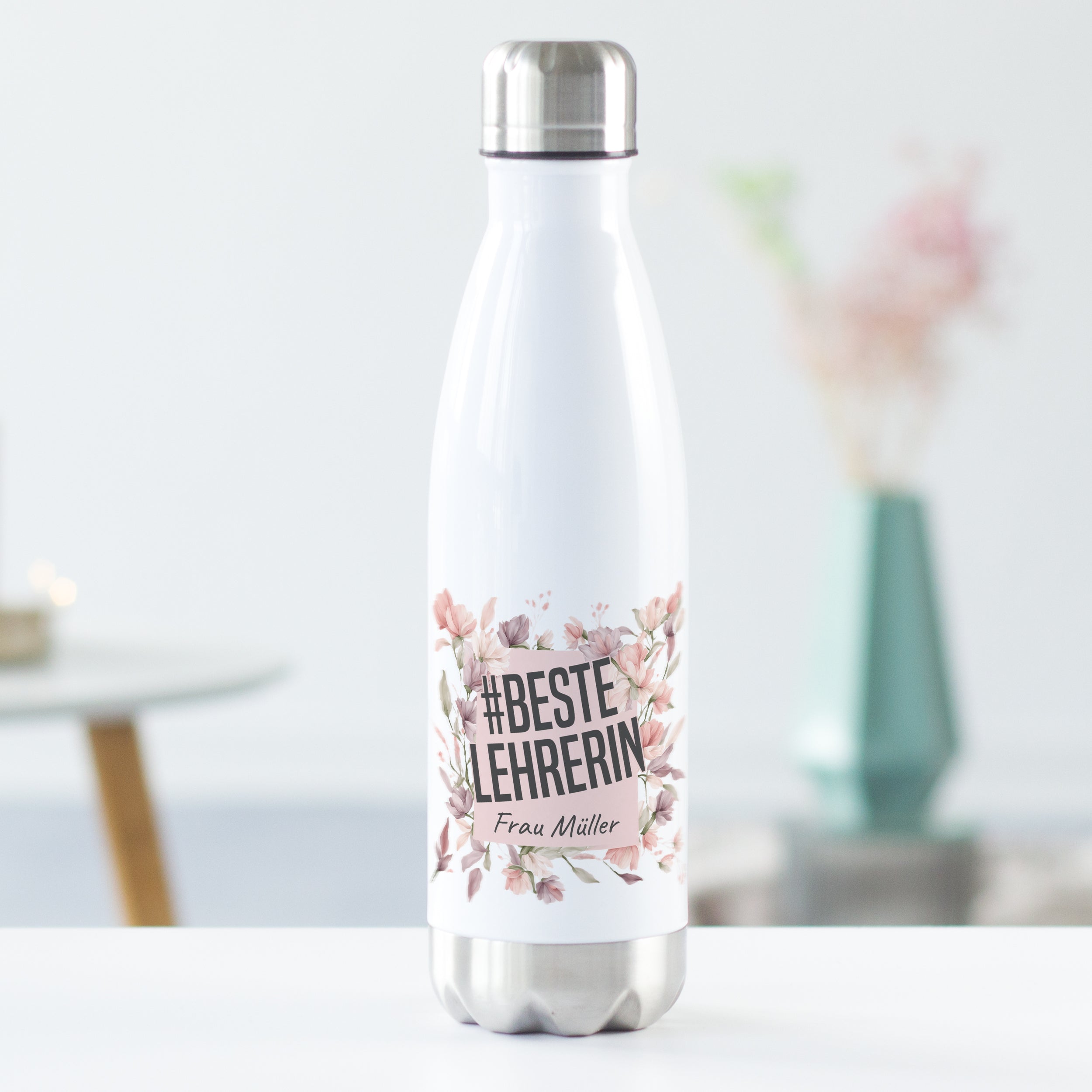 Weiße Edelstahl-Trinkflasche mit floralem Design und Aufschrift.