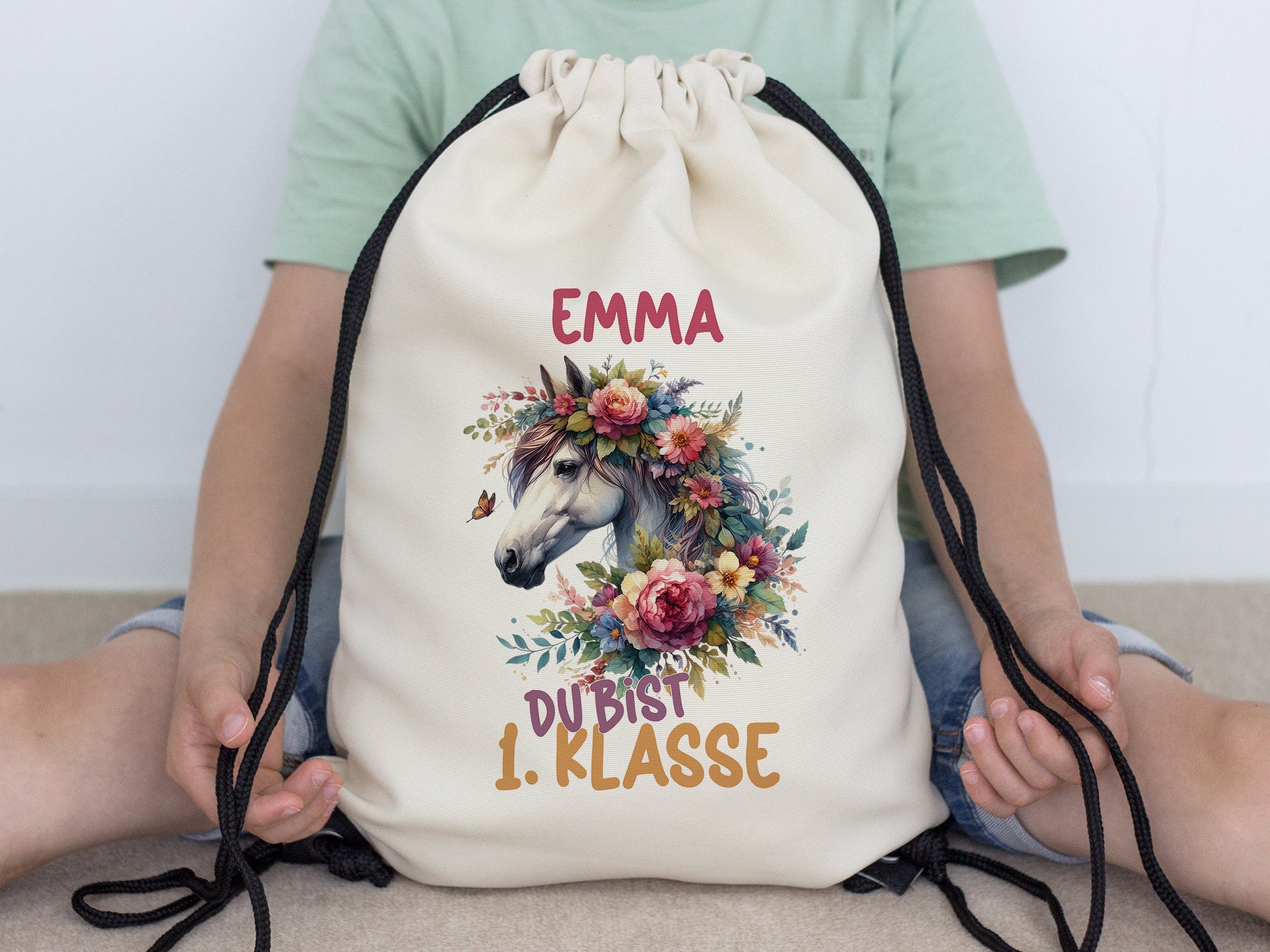 Beige Turnbeutel mit Einhorn-Motiv und bunten Blumen.