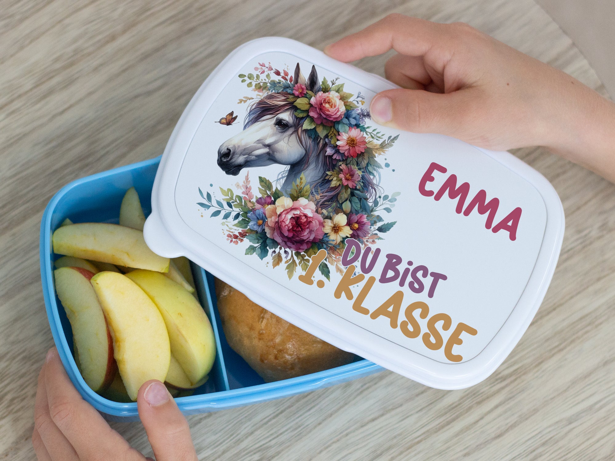 Bunte Brotdose mit Einhorn-Motiv, Äpfeln und Brötchen.