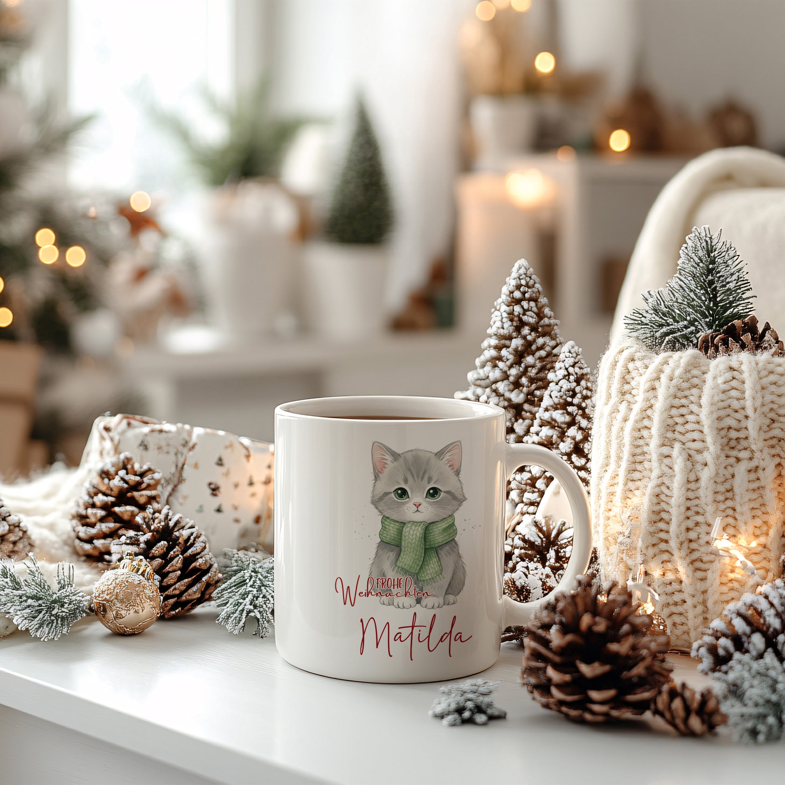 Weiße Tasse mit grauer Katze und grünem Schal.
