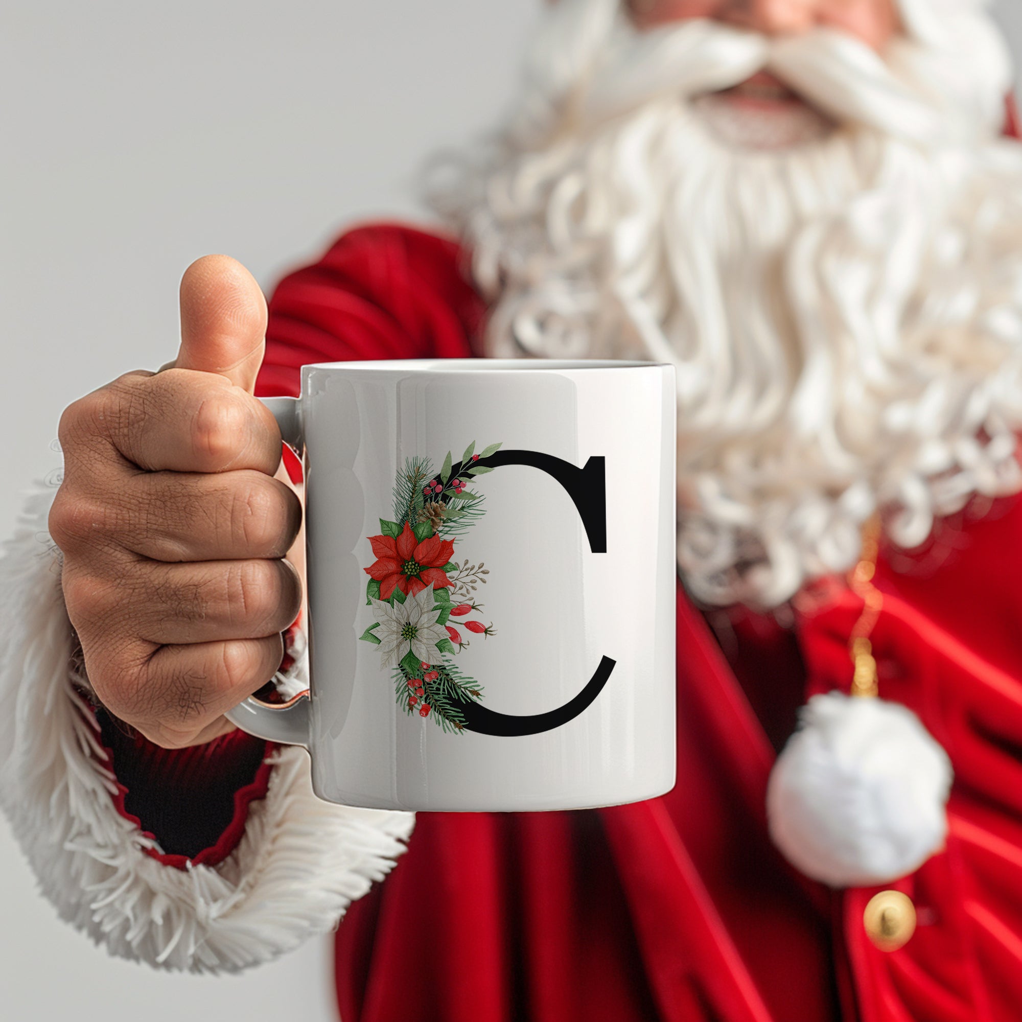 Weißer Becher mit schwarzem Buchstaben "C" und Weihnachtskranz.