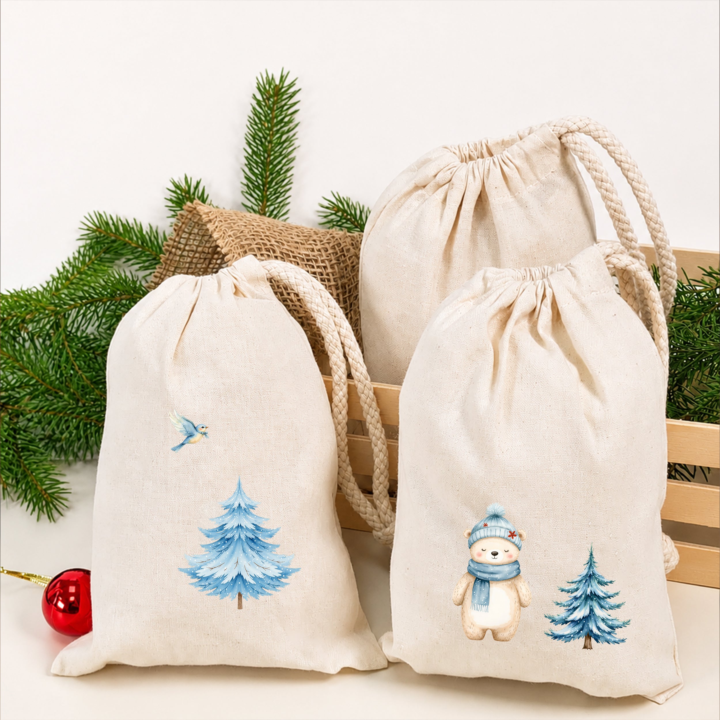 Naturfarbene Stoffsäckchen mit aufgebügelten Wintermotiven wie Fuchs, Bär, Vogel und blauen Tannenbäumen