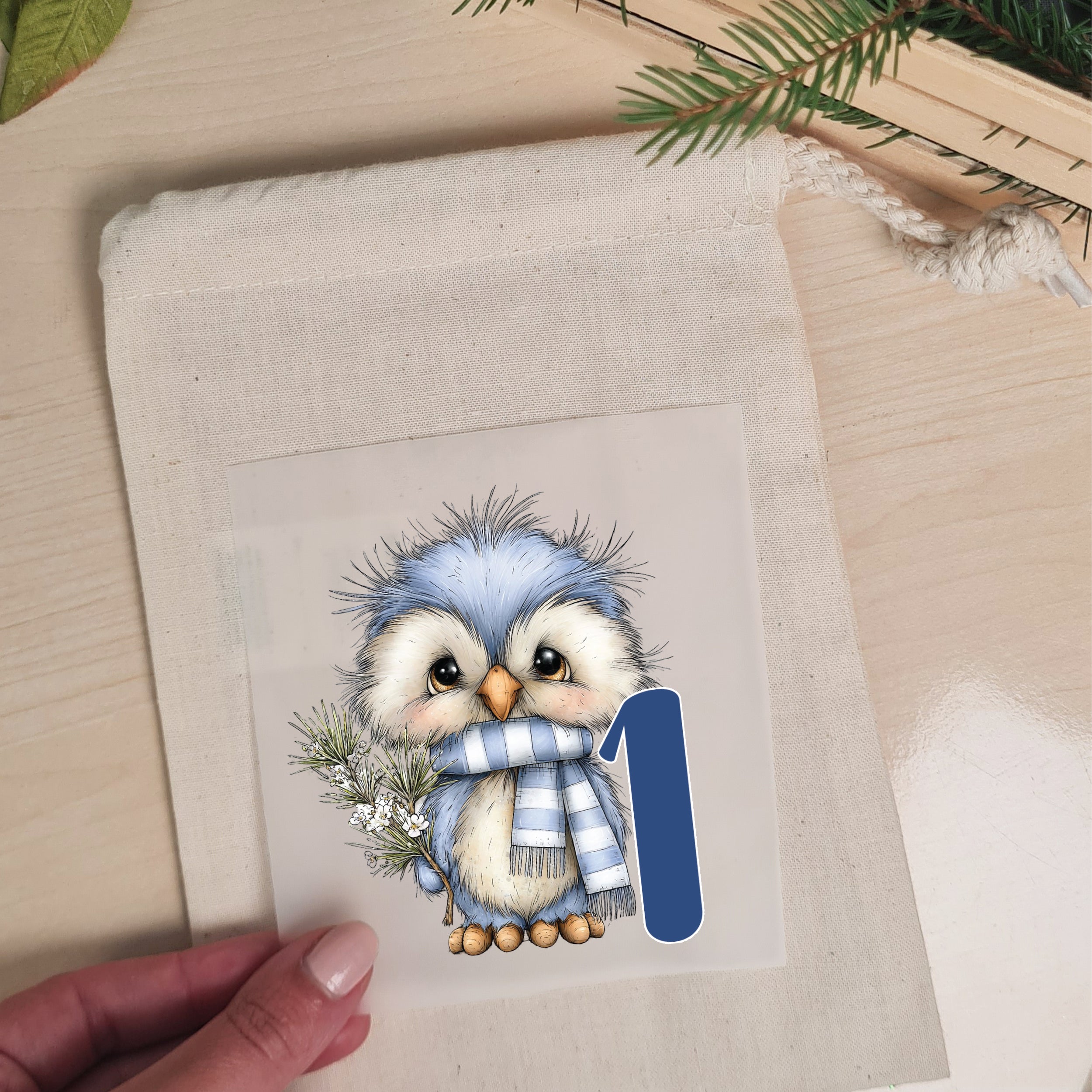Bügelbild mit Wintereule und Zahl 1 wird auf einen naturfarbenen Stoffbeutel aufgelegt