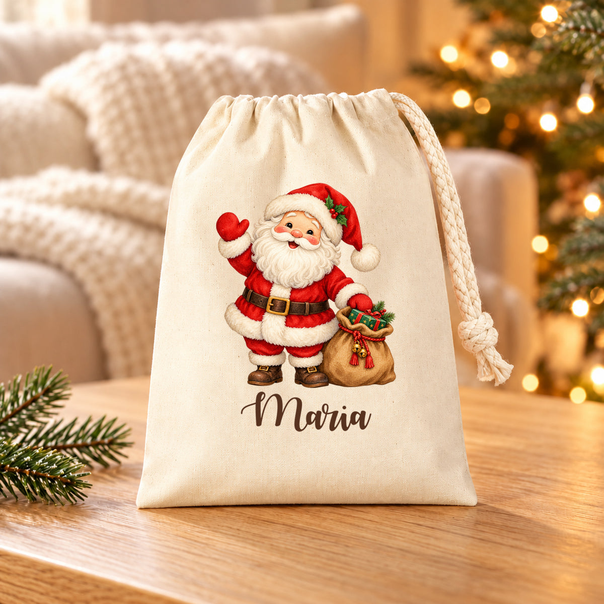Naturfarbenes Nikolaussäckchen mit Weihnachtsmann mit Geschenkesack und personalisiertem Namen auf einem Holztisch vor Sofa und Weihnachtslichtern.