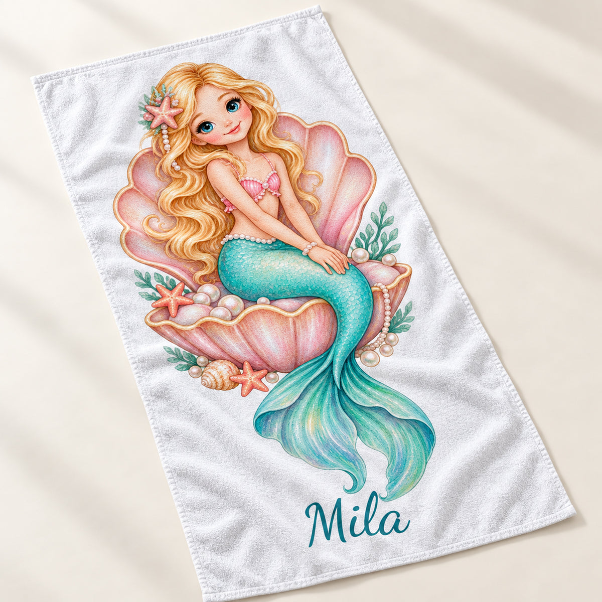 Handtuch mit Motiv Perlenmuschel und Beispielname Mila, schräg von oben gezeigt.