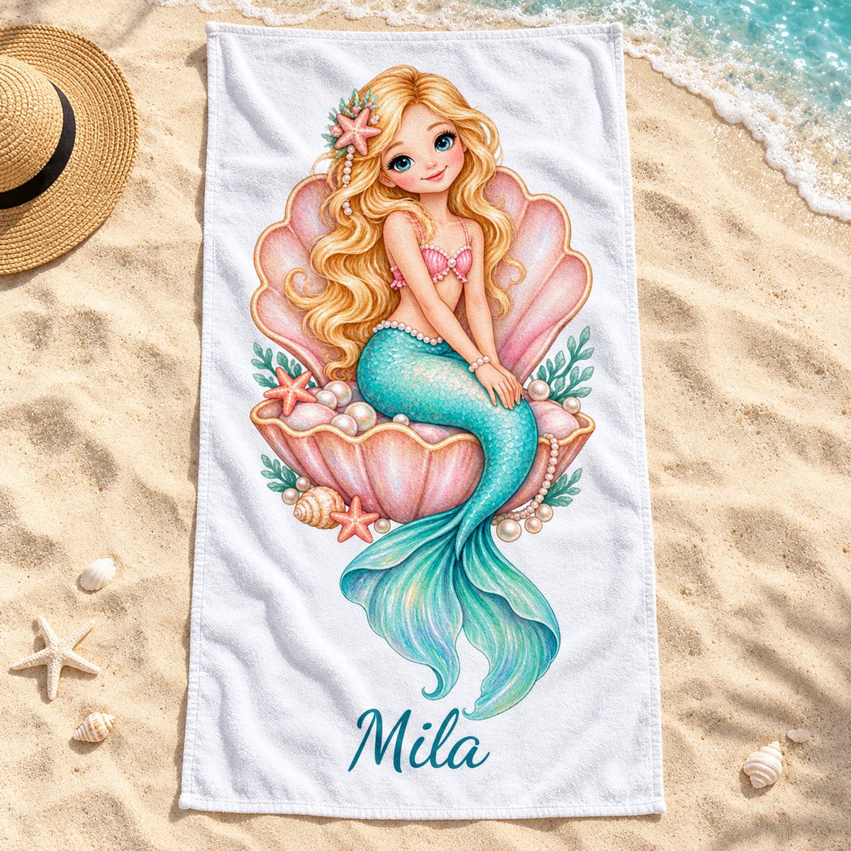 Handtuch mit Meerjungfrauenmotiv Perlenmuschel und Beispielname Mila auf Sand am Strand.