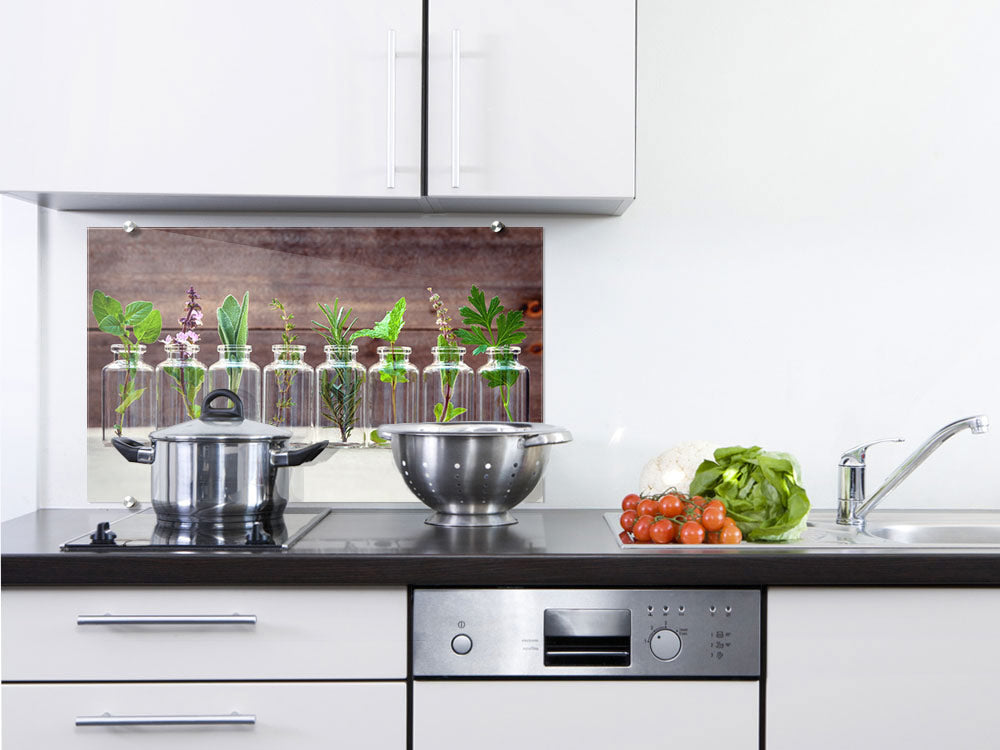 Küchenrückwand mit Kräutern in Glasflaschen, grün und braun.