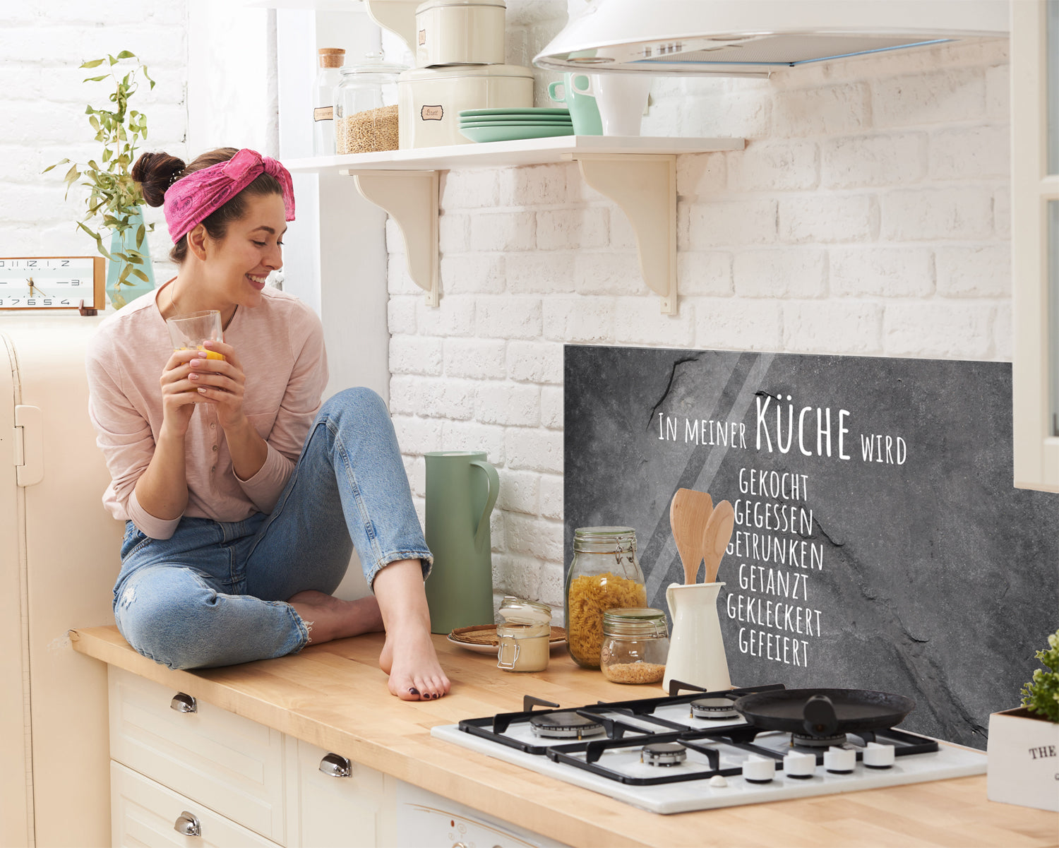Schwarze Küchenwand mit weißem Schriftzug und Frau mit Getränk.