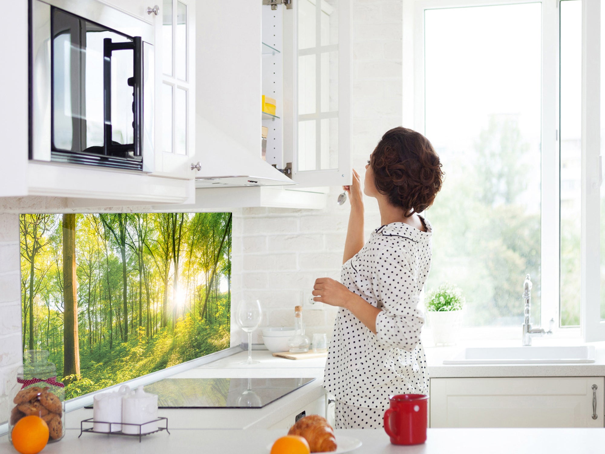 Küche mit Waldtapete, Frau in gepunktetem Pyjama, helle Farben.