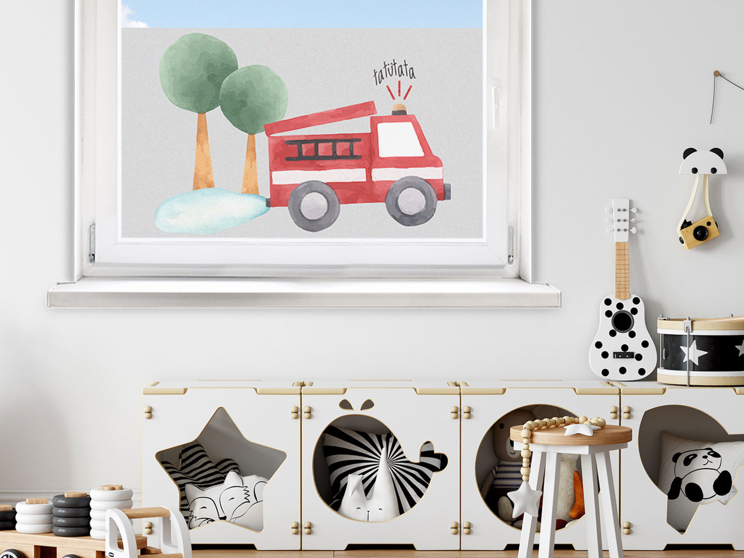 Rotes Feuerwehrfahrzeug vor grünen Bäumen und blauem Himmel.