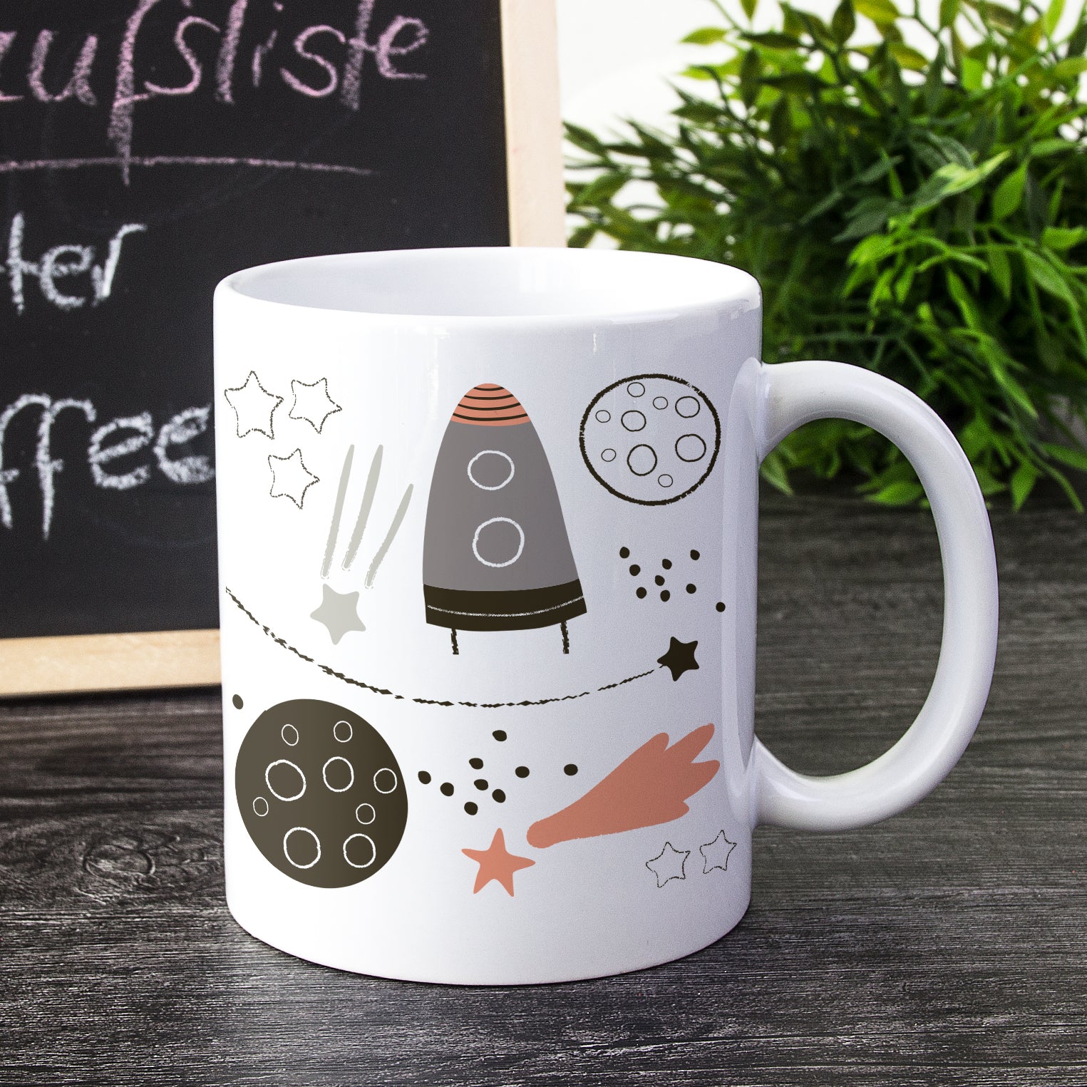 Weißer Kaffeebecher mit Rakete und Planeten-Motiv.