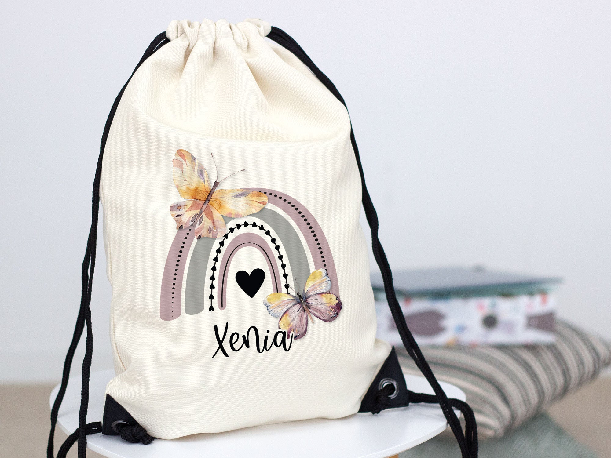 Beiger Rucksack mit Regenbogen und Schmetterlingen, personalisiert.