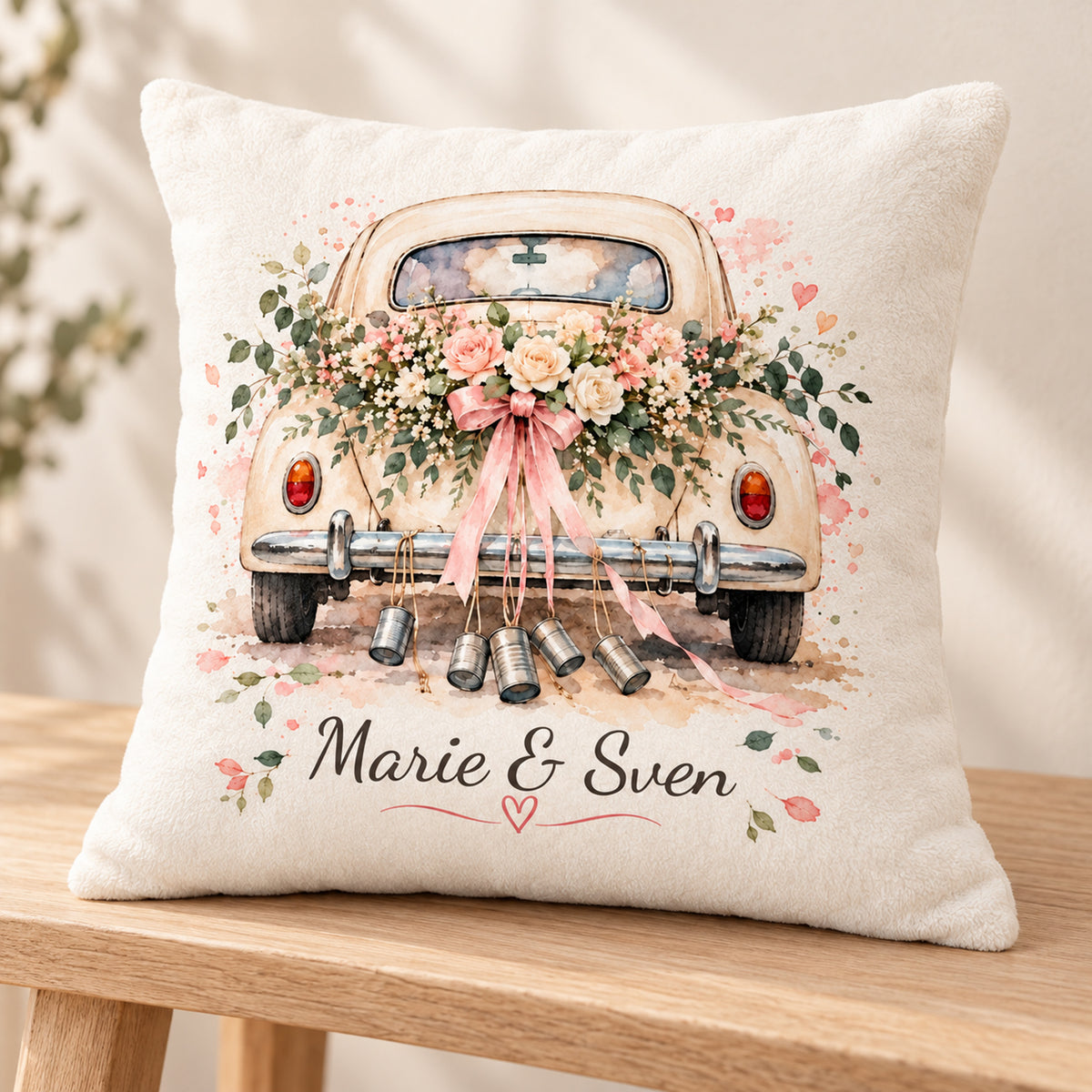 Kissenbezug mit Hochzeitsauto-Motiv schräg auf einer Holzbank.