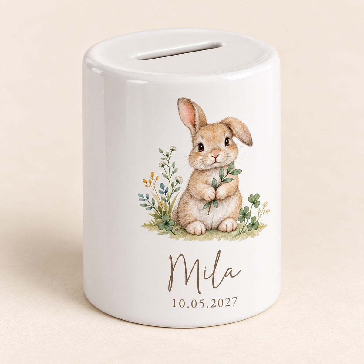 Hase mit Blätterzweig: Spardose mit Beispielname Mila und Datum 10.05.2027, Schrägansicht