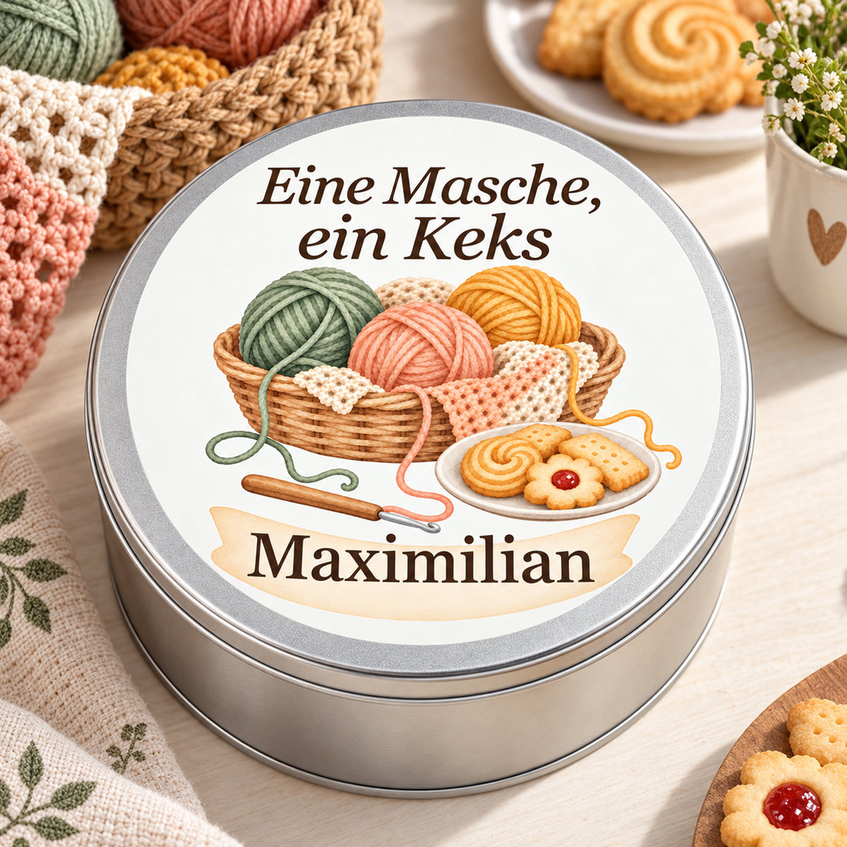 Nahansicht der Keksdose mit Wollkorb, Häkelstück und Keksteller, Spruch und Namensfeld.