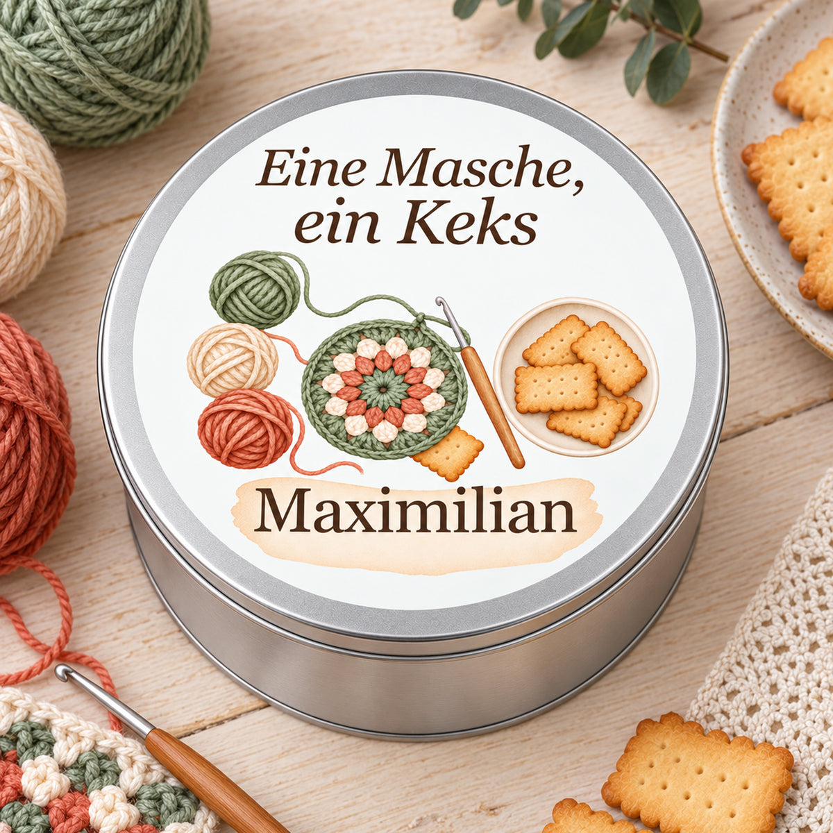 Draufsicht auf die Keksdose mit rundem Häkelstück, Wollknäueln und Keksen in einer hellen Häkelszene.