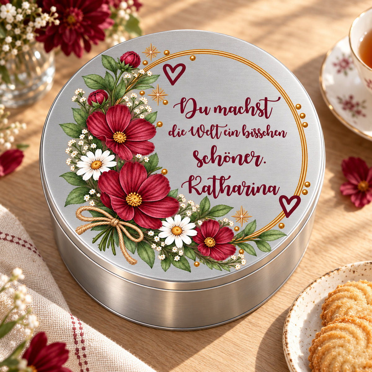 Blumen-Keksdose neben Tee, Keksen und Blumen auf einem Holztisch – Motiv „Welt schöner“