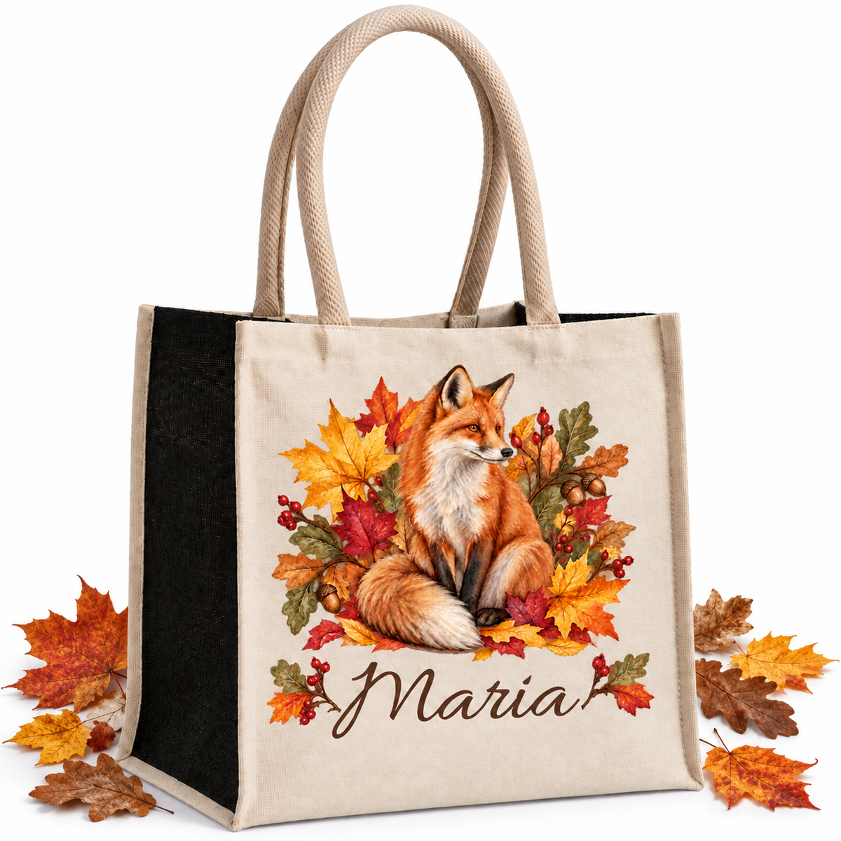 Baumwoll-Jute-Tasche mit Fuchs und Herbstlaub und Wunschname, naturfarbene Front und schwarze Seiten, mit echten Herbstblättern neben der Tasche auf hellem Hintergrund.