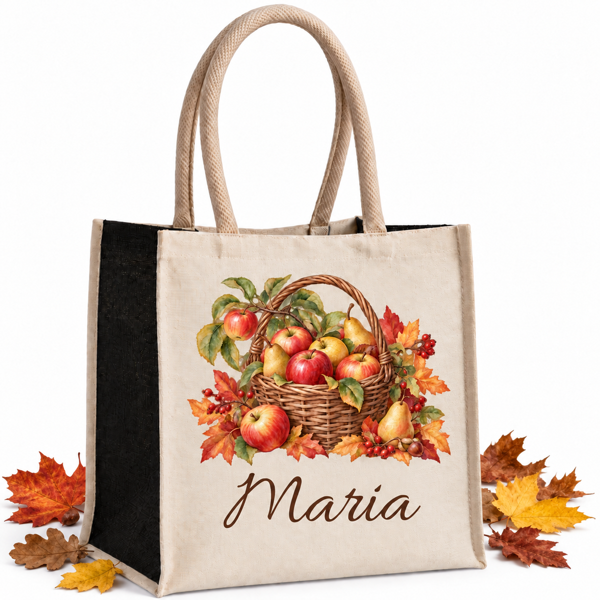 Baumwoll-Jute-Tasche mit Apfelkorb und Wunschname, naturfarbene Front und schwarze Seiten, mit echten Herbstblättern neben der Tasche auf hellem Hintergrund.