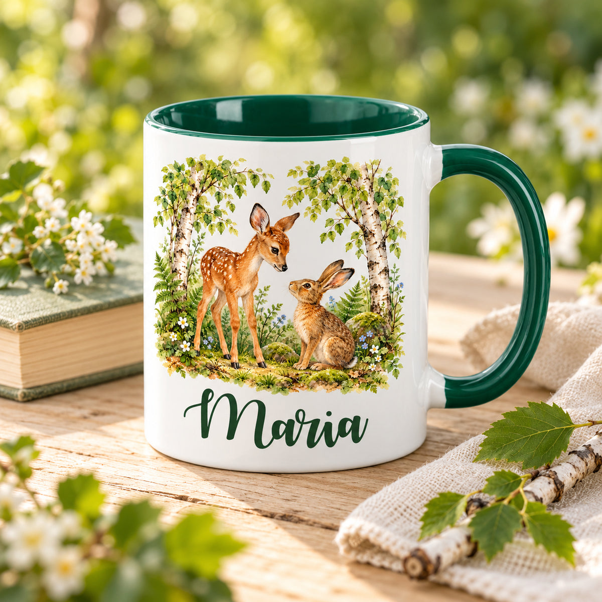 Namenstasse mit Rehkitz und Hasen auf einem Holztisch neben Buch und Naturdekoration.