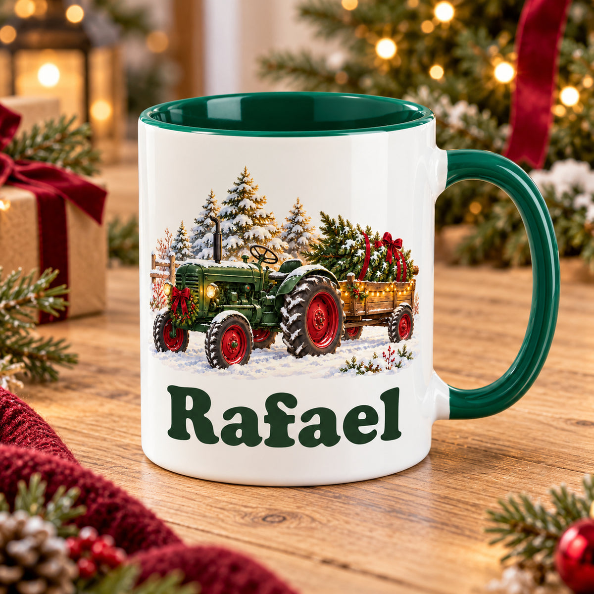 Weiße Tasse mit grünem Henkel und Innenraum, Trecker mit Tannenbaum und Wunschname schräg auf einem Holztisch.