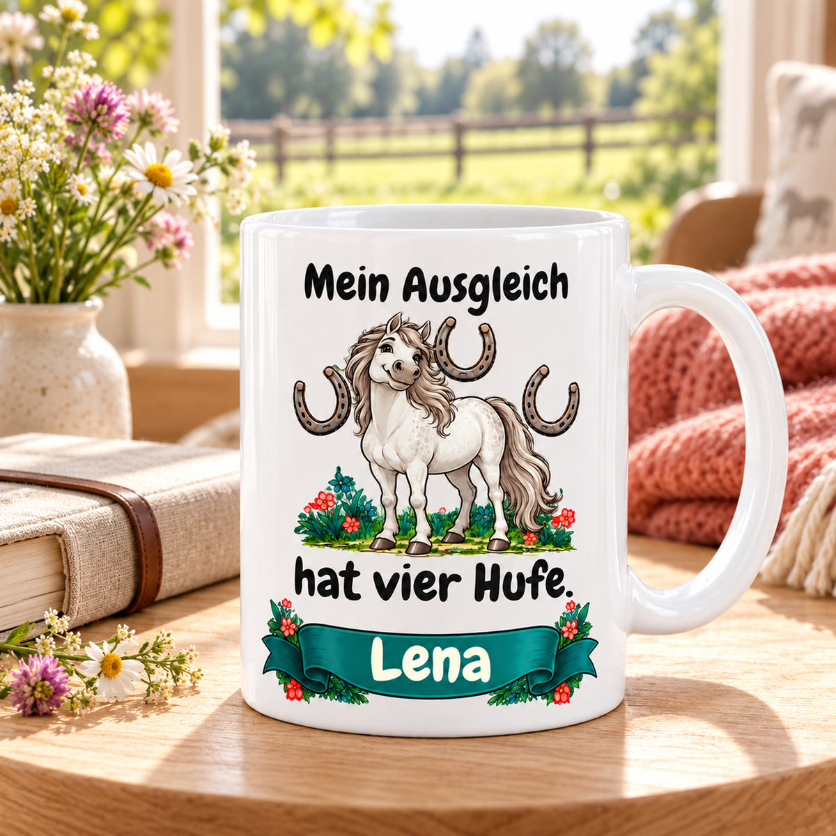 Weiße Pferdetasse mit Namen, Schimmel und Hufeisen und Spruch „Mein Ausgleich hat vier Hufe.“, in einer gemütlichen Reitstall-Umgebung.
