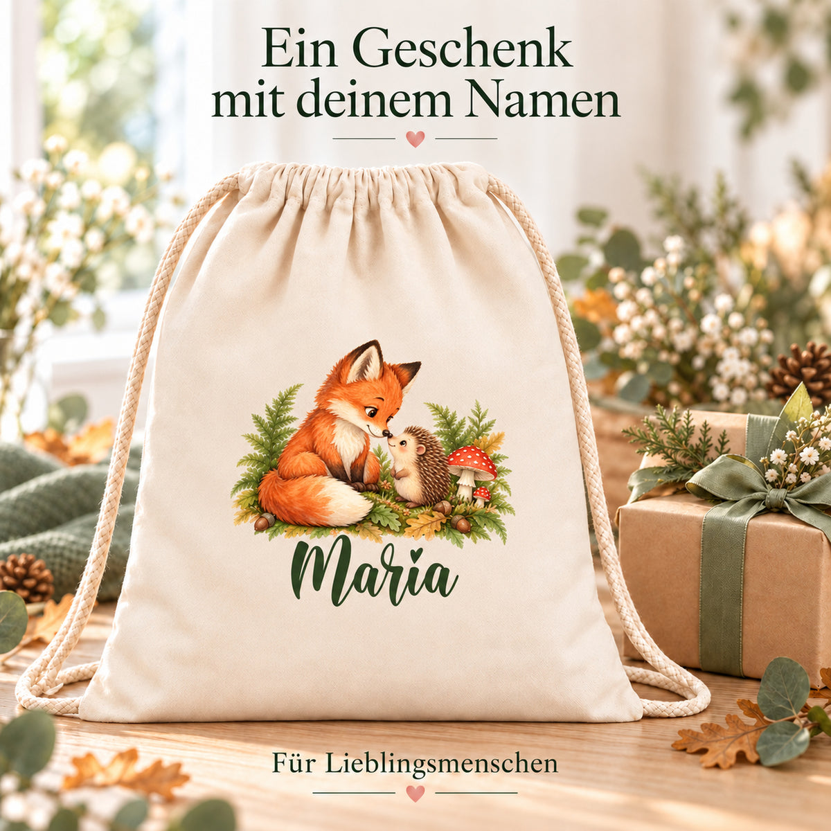 Personalisierter Turnbeutel mit Fuchs und Igel neben einem Geschenk mit grüner Schleife