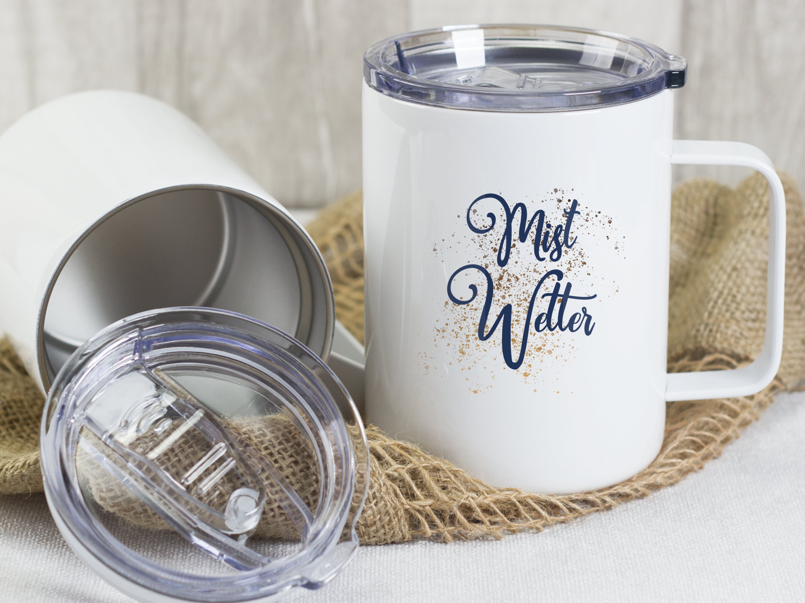 Weißer Becher mit "Mist Wetter"-Aufdruck und klarem Deckel.