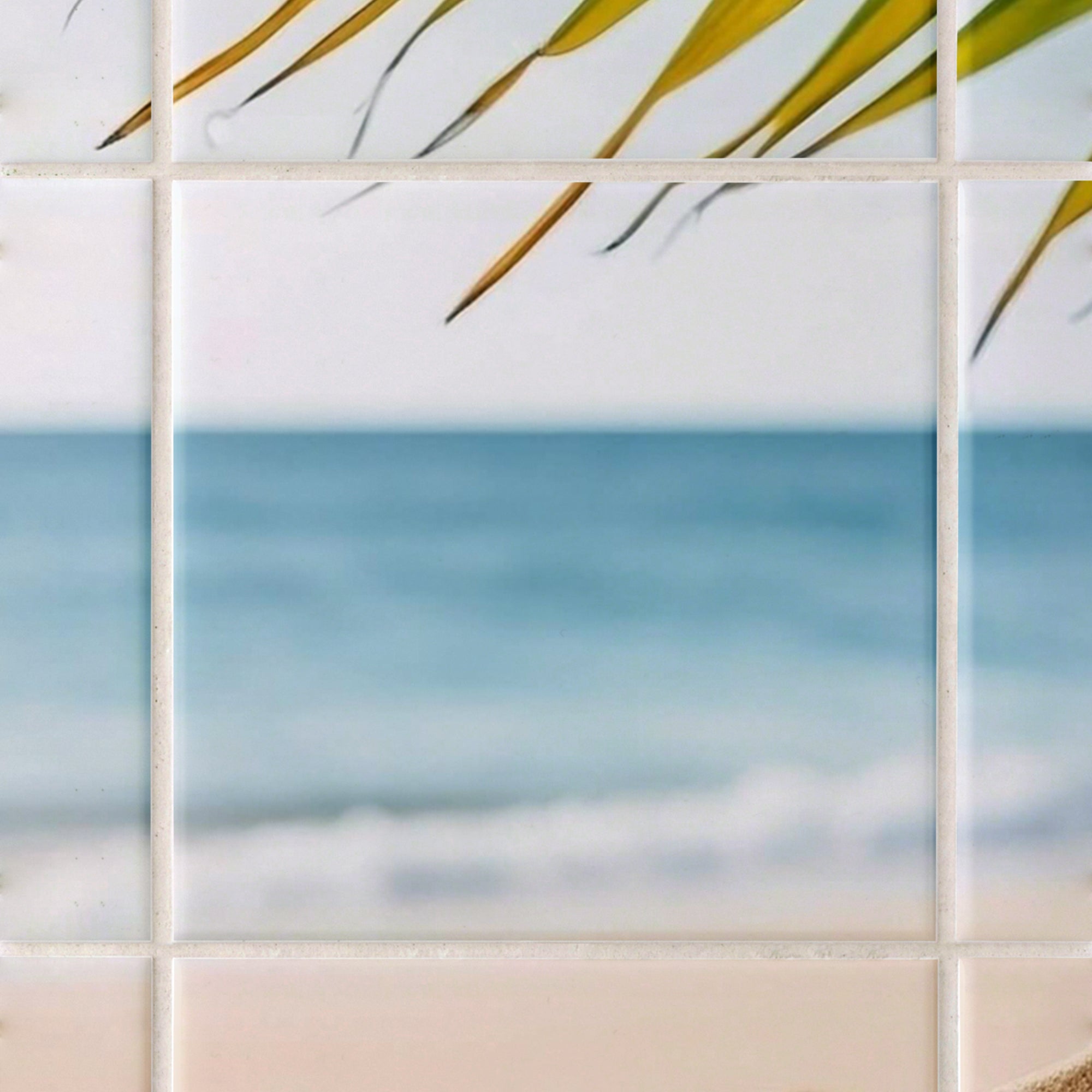 Fliesen mit Strandmotiv, blaues Wasser und grüne Blätter.