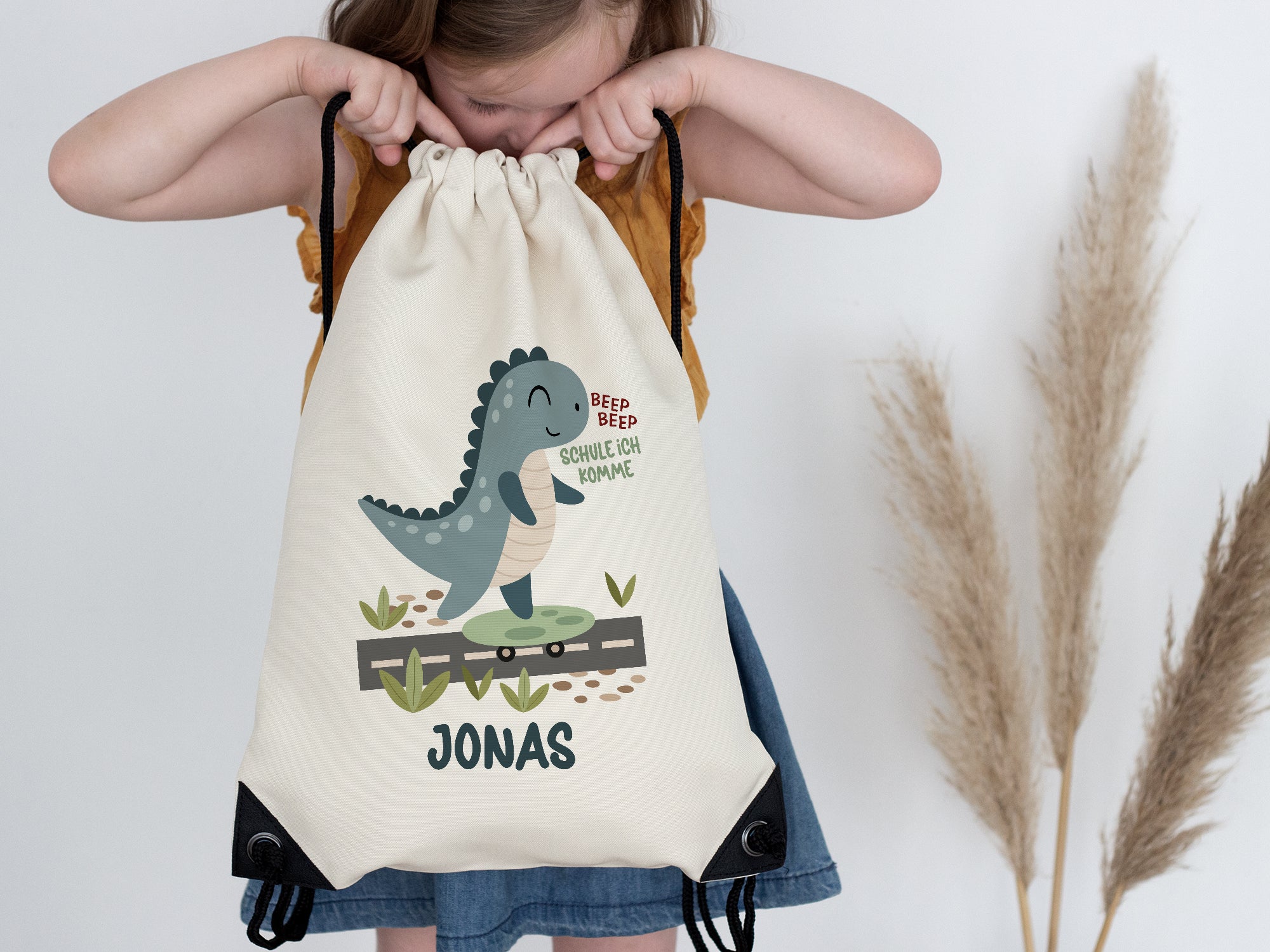 Beiger Rucksack mit Dinosaurier-Motiv und Namen Jonas.