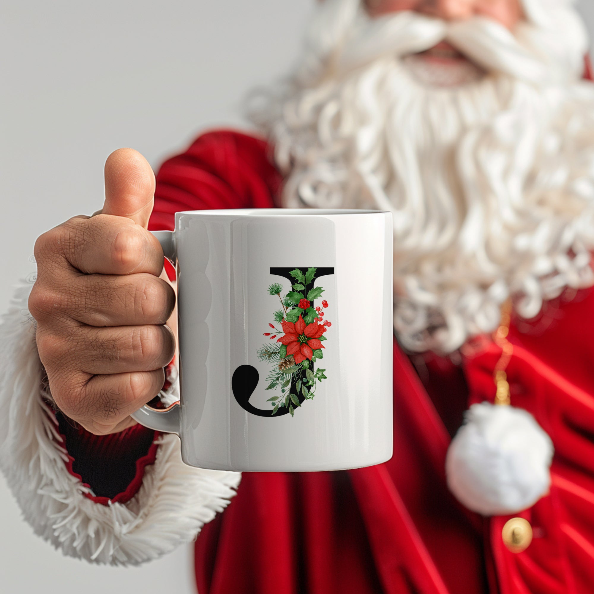 Weißer Becher mit floralem "J" und Weihnachtsmotiven.