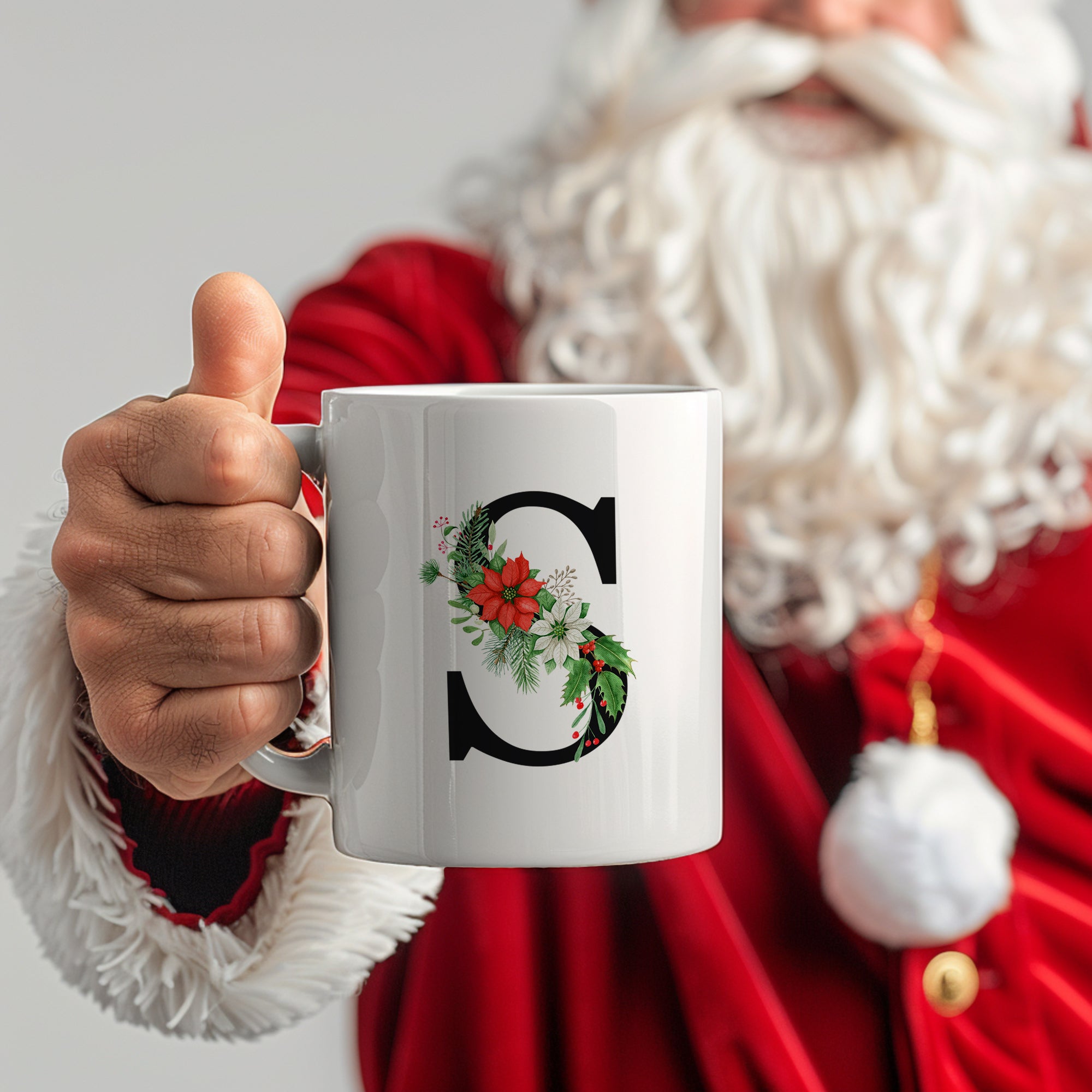 Weißer Becher mit floralem "C" und Weihnachtsmotiven.