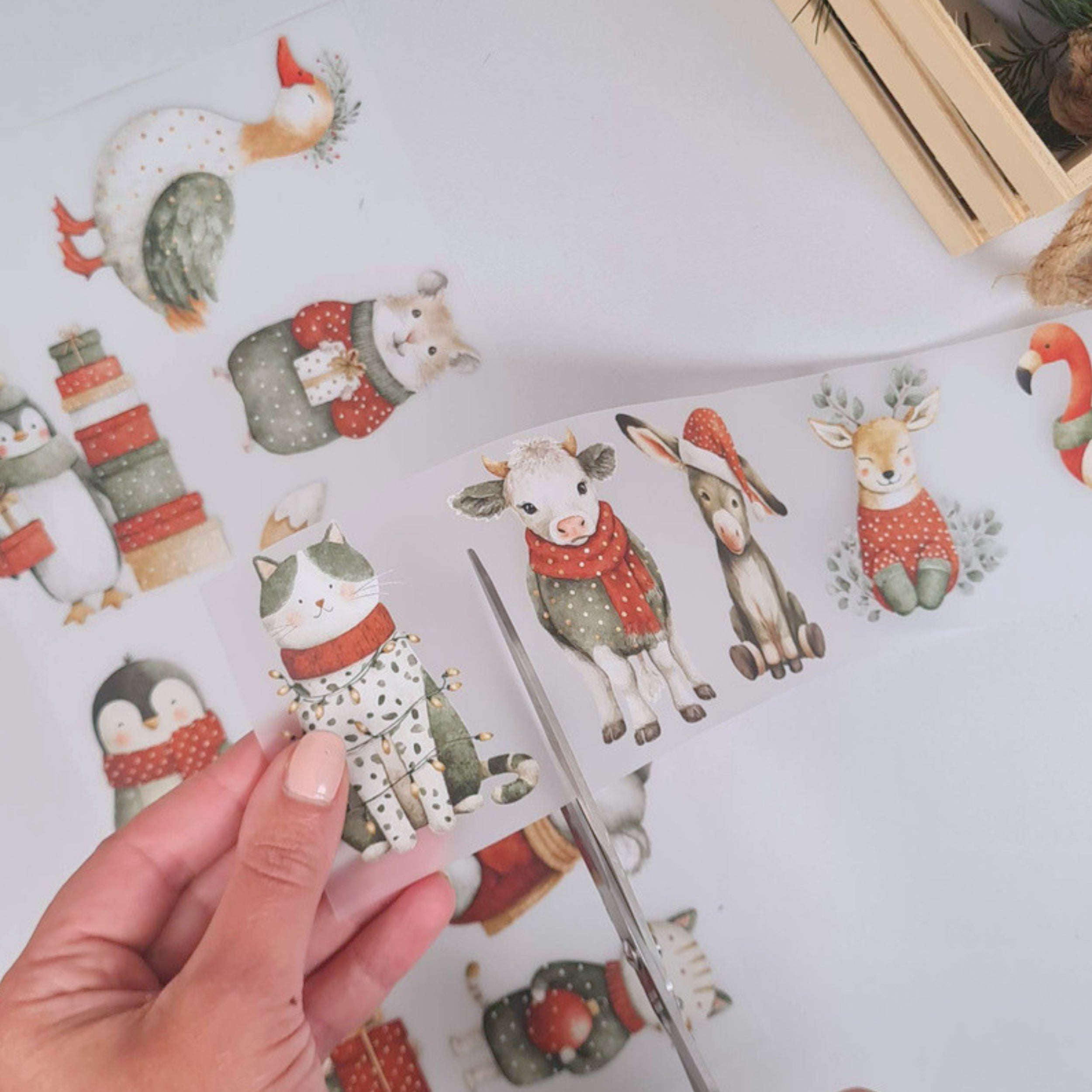 Einzelne weihnachtliche Tiermotive werden mit einer Schere aus dem Bügelbildbogen ausgeschnitten