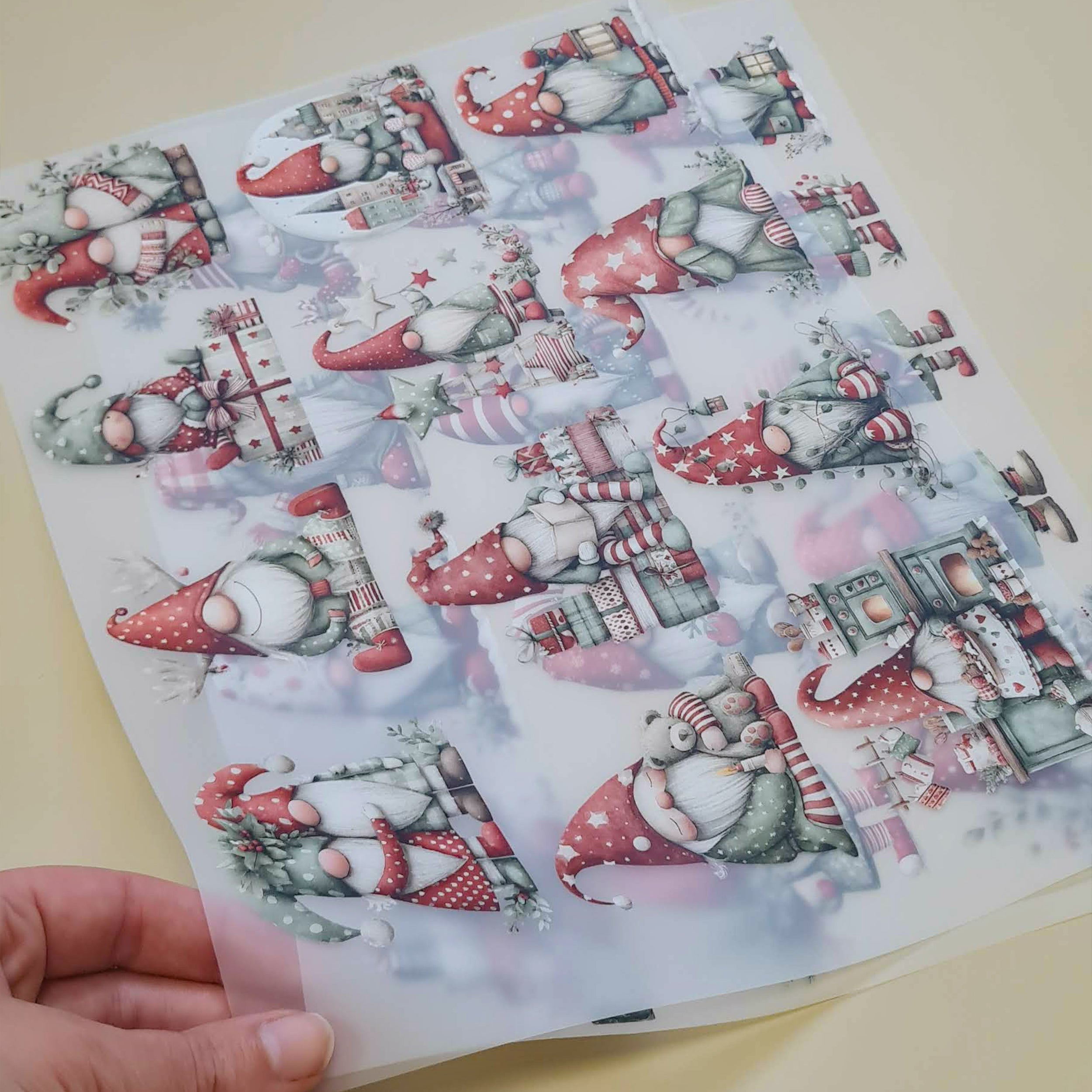 Nahaufnahme von zwei transparenten Bügelbildbögen mit Weihnachtswichteln und Geschenken