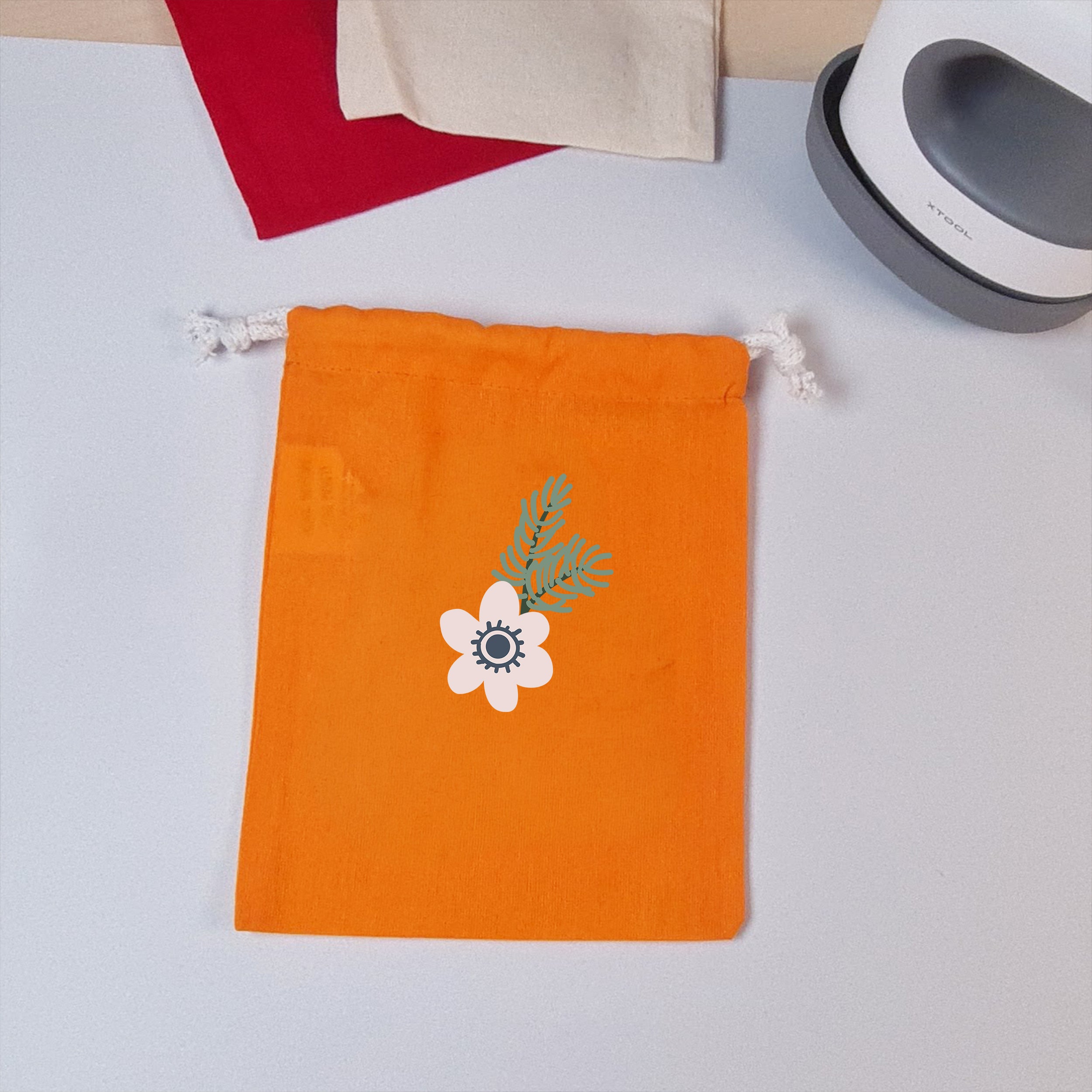 Orangefarbener Stoffbeutel mit aufgebügelter Winterblume und Tannenzweigen