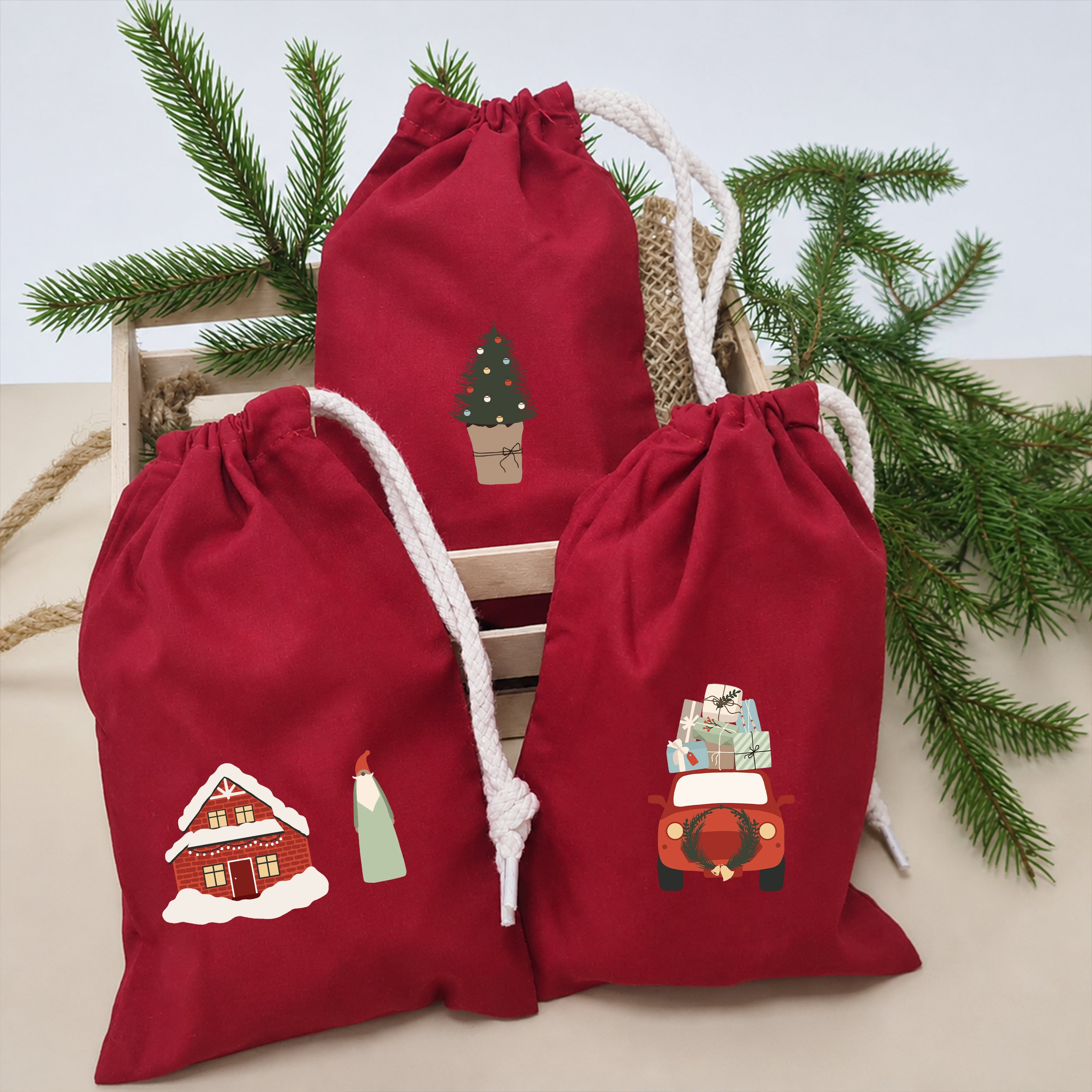 Rote Stoffsäckchen mit aufgebügelten Weihnachtsmotiven wie Haus, Wichtel, Tannenbaum und Auto