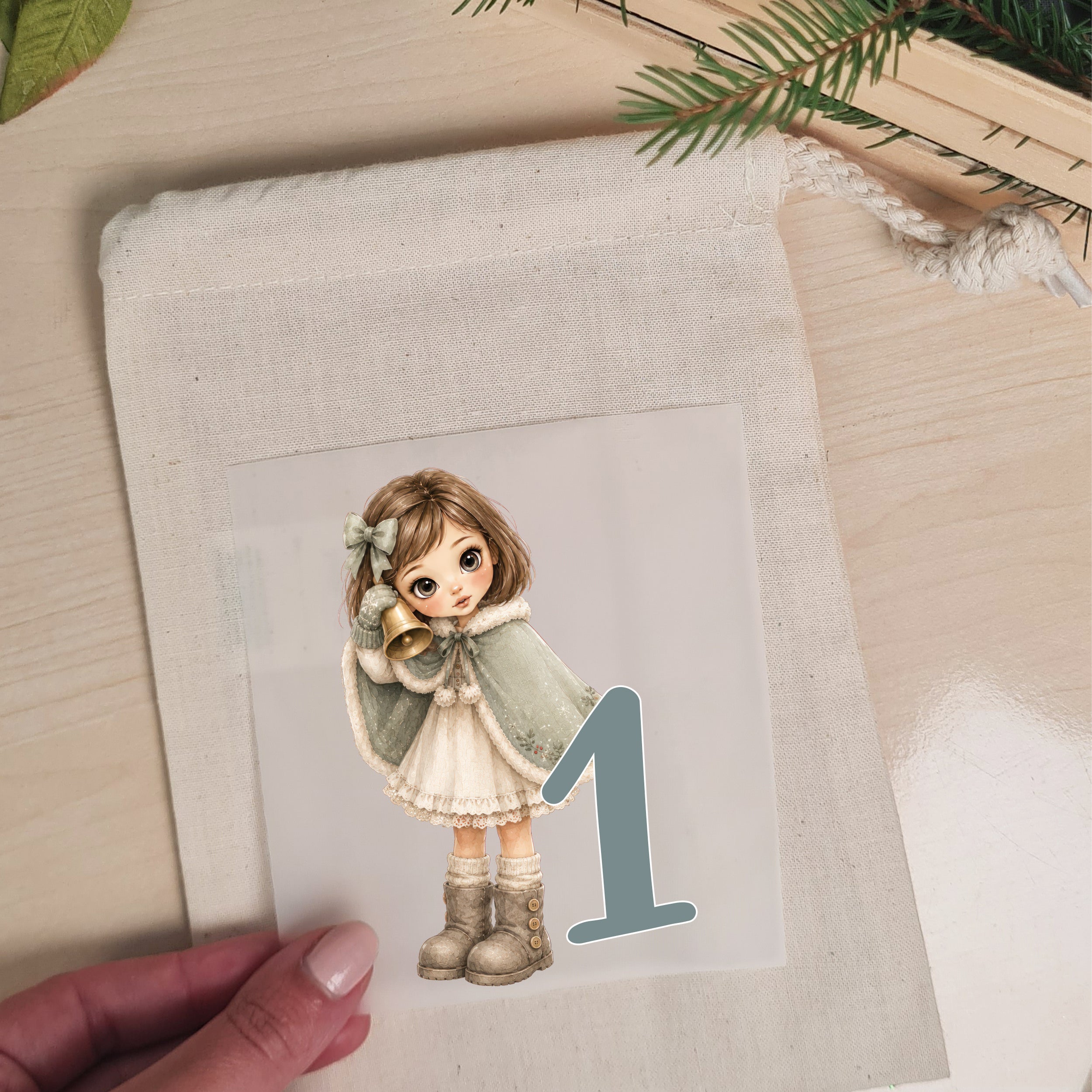 Bügelbild mit Wintermädchen und Zahl 1 wird auf einen naturfarbenen Stoffbeutel aufgelegt
