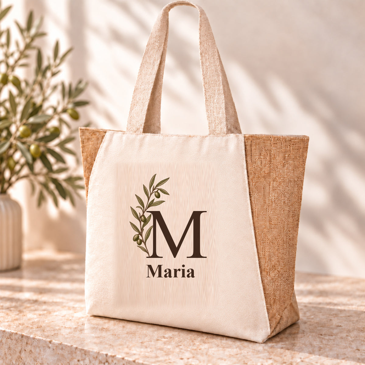 Personalisierter Shopper mit seitlicher Olivenranke, Initial und Wunschname auf naturfarbener Front.