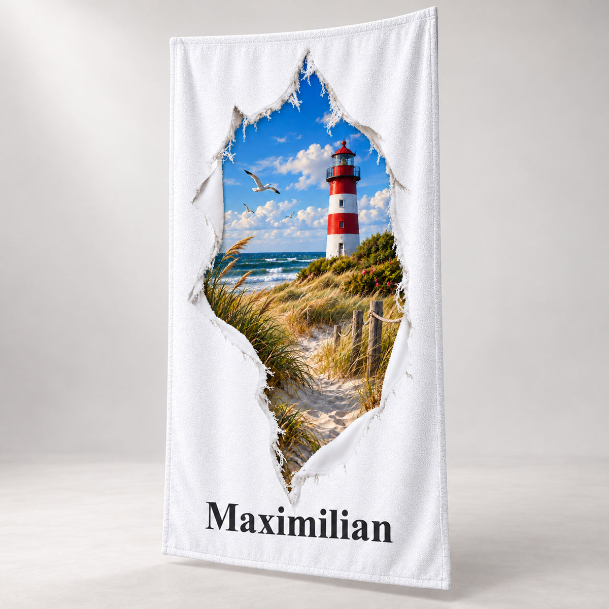 Handtuch mit Ostsee-Leuchtturm in Rissoptik und Wunschname, schräg vor hellem Hintergrund